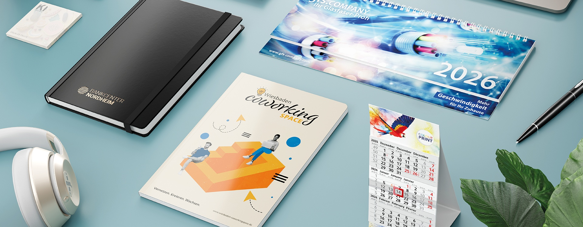 Geiger Tisch- und Wandkalender mit Notizbüchern auf einer hellblauen Arbeitsfläche
